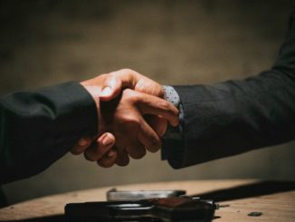 two people shaking hands over a wooden table