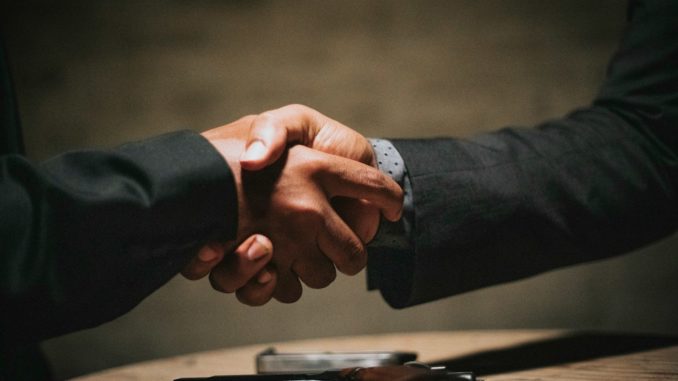 two people shaking hands over a wooden table